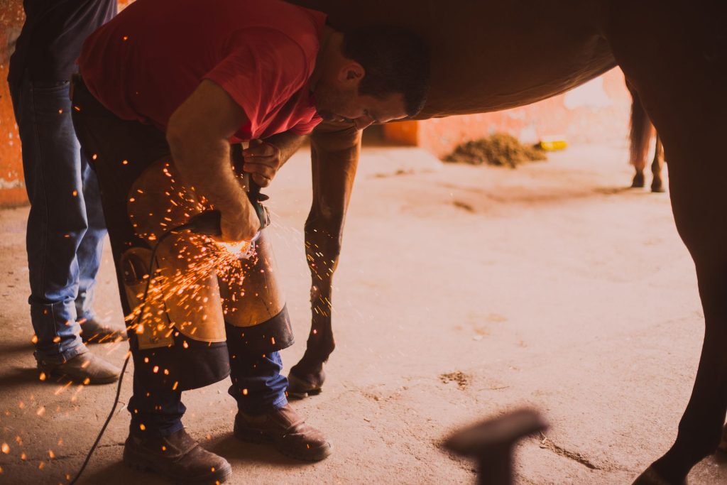 Farrier shoeing a horse with sparks flying